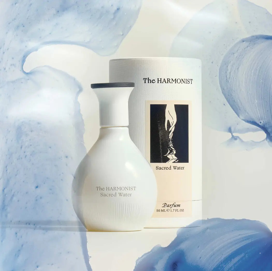 The Harmonist Sacred Water perfume bottle and packaging set against a soft, fluid blue and white background.