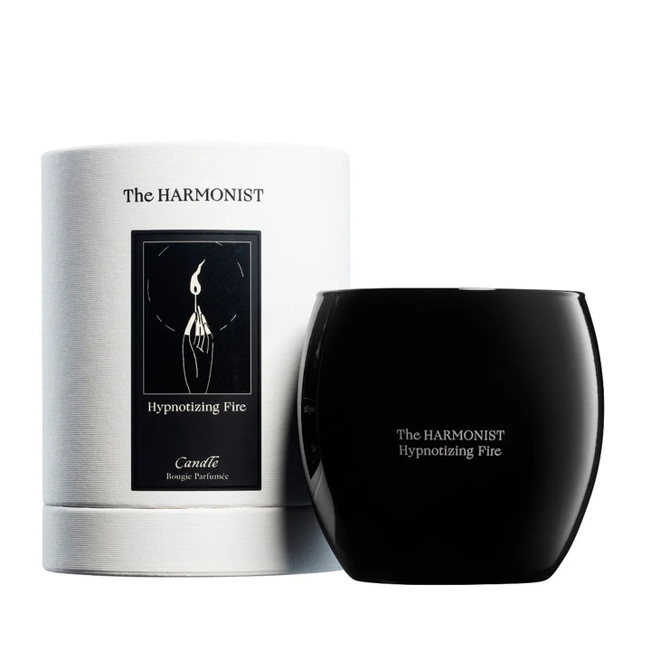 The Harmonist Hypnotizing Fire candle with black glass container and white cylindrical packaging.